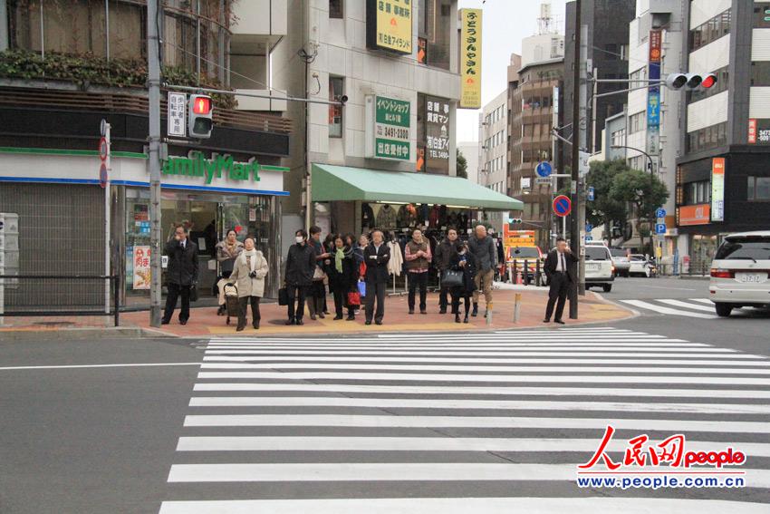 日本东京，阴冷的街上，行人正安静等待红灯