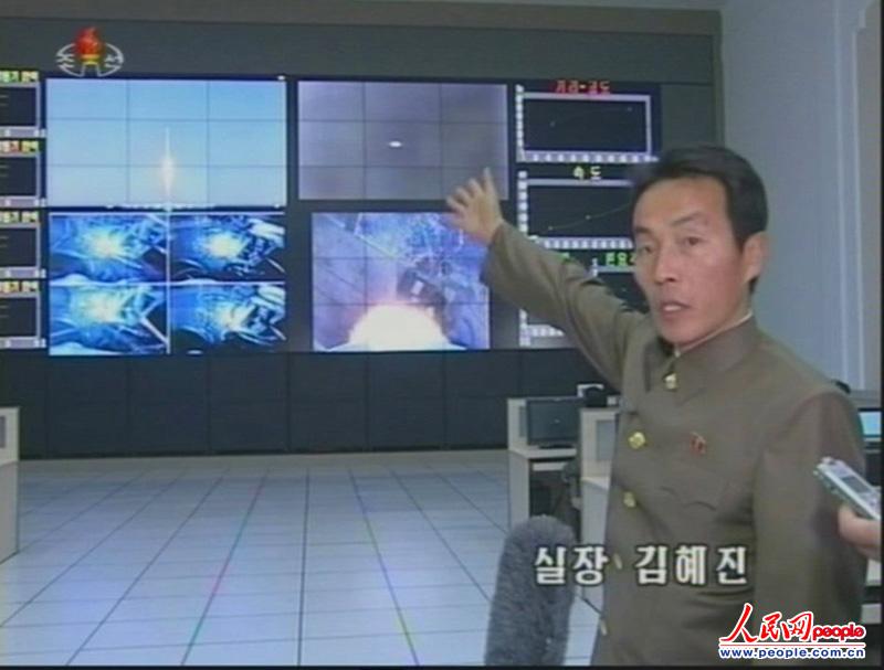 当地时间2012年12月12日，朝鲜火箭科学家在平壤卫星控制综合指挥所里接受采访，身后的大屏幕在转播远程火箭“银河3号”发射场面。（来源：东方IC 版权所有，违者必究）