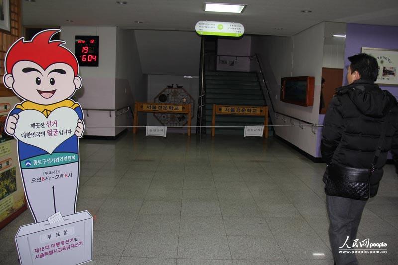 5.投票所门口的时钟显示时间为早上6点04分，陆续有选民前来投票，投票所门口的牌子上写着：“干净的总统选举代表韩国的形象”。人民网记者 马菲 摄