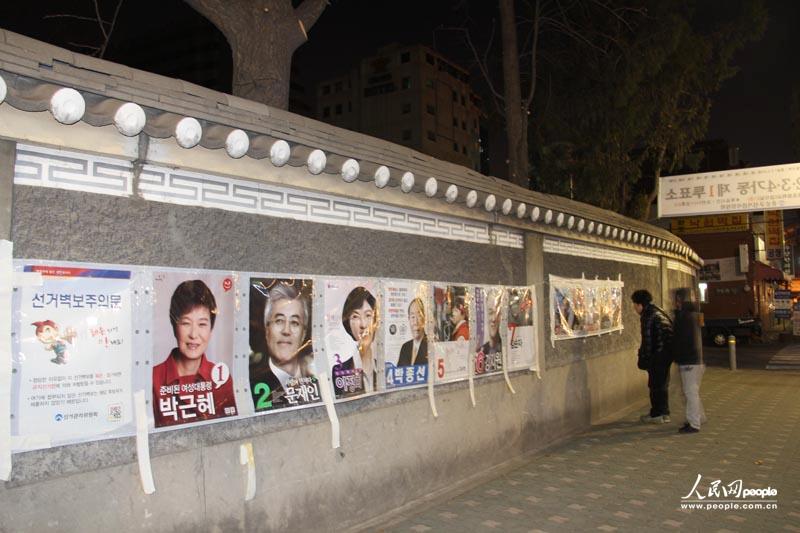 7.在首尔一处投票所的外面，民众在看几位候选人的海报，他们当中的一位将决定在未来5年韩国的发展方向。人民网记者 马菲 摄
