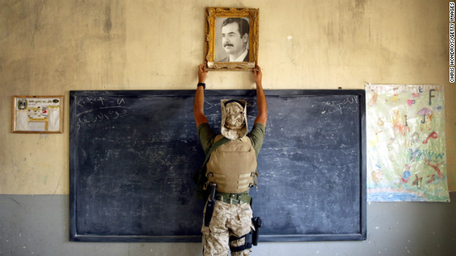 2003年4月16日，一名美国海军陆战队员摘下了伊拉克库特一所小学教室里的萨达姆相片。（图片来自CNN网站）