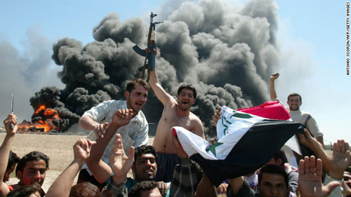 2004年4月9日，伊拉克武装分子挥舞着国旗，庆祝他们用榴弹击中了美军的军用加油机。（图片来自CNN网站）