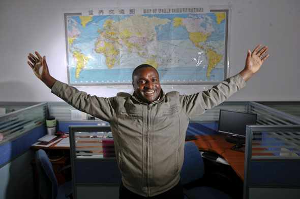 2013年3月21日，坦桑尼亚商人雅各布站在他的中国贸易伙伴办公室内的世界地图前。七年前来到义乌的雅各布，目前每年往返非洲三到四次，在义乌的生意主要以采购五金产品、纺织品为主。摄影：新华社记者  崔新钰