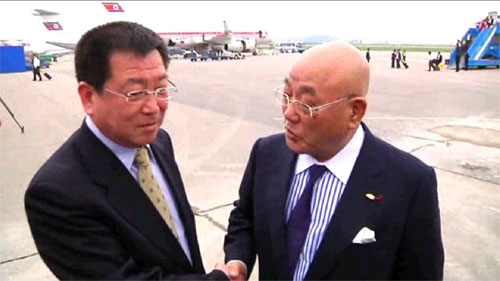 图为饭岛勋（右）和前来迎接的朝鲜外务省亚洲局负责日本事务的副局长金哲虎正在握手。（朝中社视频截图） 点击图片进入下一页！