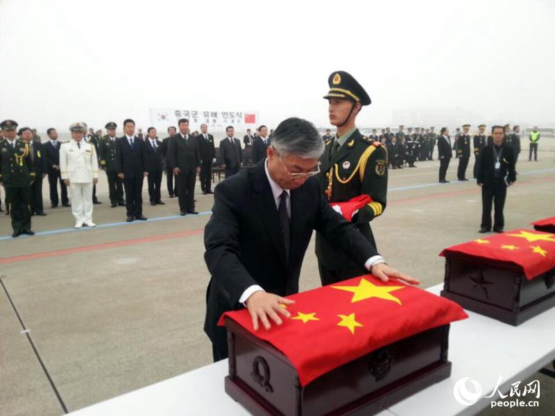中国驻韩国大使邱国洪为烈士遗骸覆盖国旗。