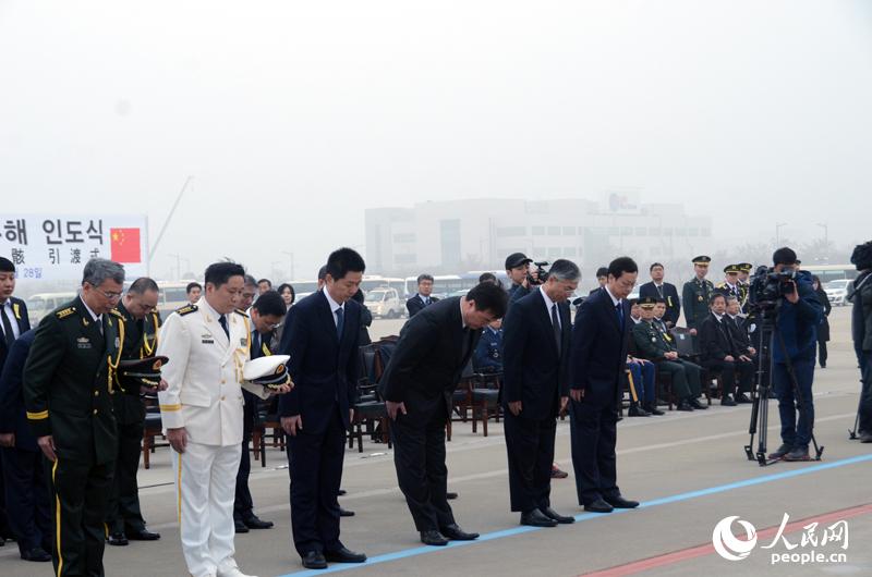 中方代表团向烈士遗体鞠躬。