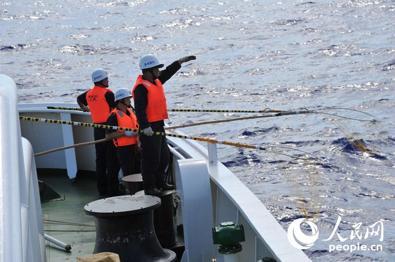 4月1日，“海巡01”在澳方今日公布的重点搜寻片区进行疑似物打捞、排除。图为海巡01打捞组工作人员在后甲板等待打捞疑似漂浮物。张驰摄