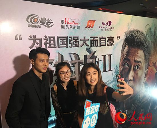 10月11日，泰国曼谷观众在《战狼2》泰国首映礼海报展板前合影。 俞懿春摄