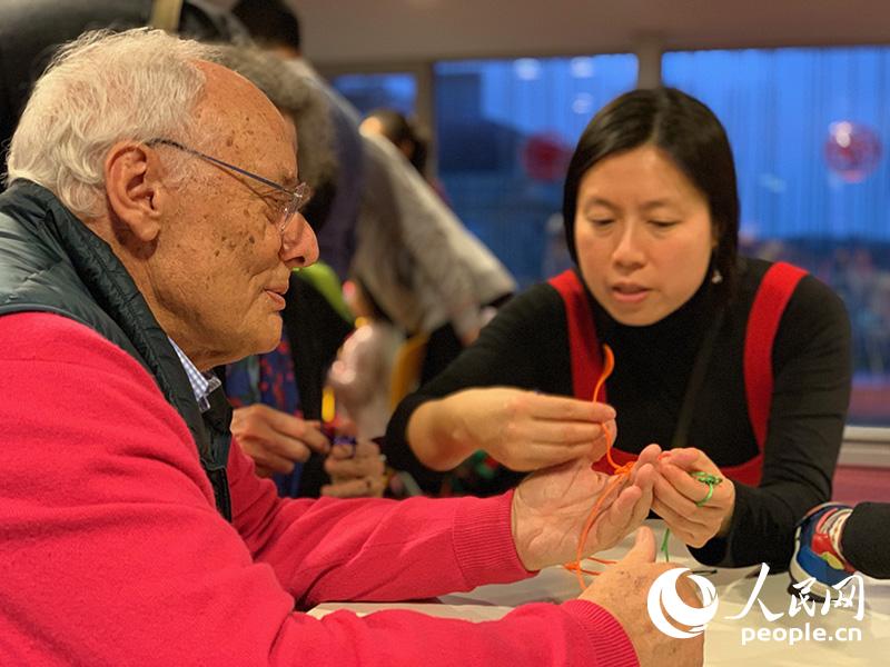图为法国民众在巴黎中国文化中心工作人员帮助下学习编织中国结。龚鸣摄