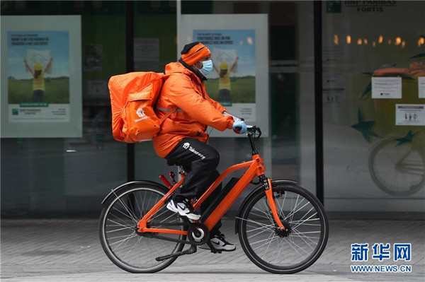 5月4日，在比利时布鲁塞尔，一名外卖员骑车送餐。 新华社记者 郑焕松 摄