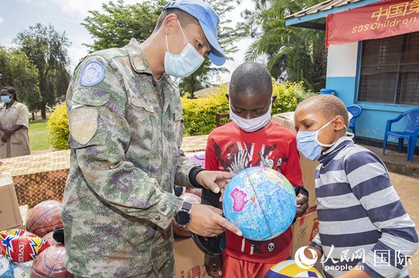 分队队员正在为儿童村的孩子们在地球仪上寻找刚果（金）位置。彭毅摄