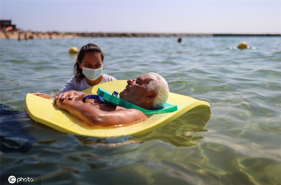 西班牙海滩救生员帮助残疾人体验海中游泳