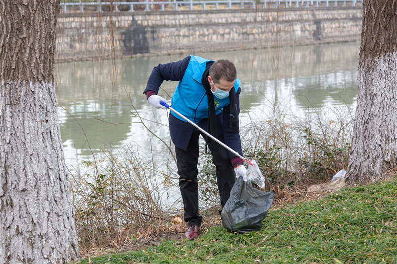 身穿天蓝色河湖监督员马甲的何诺正在清理岸边的垃圾。受访者供图