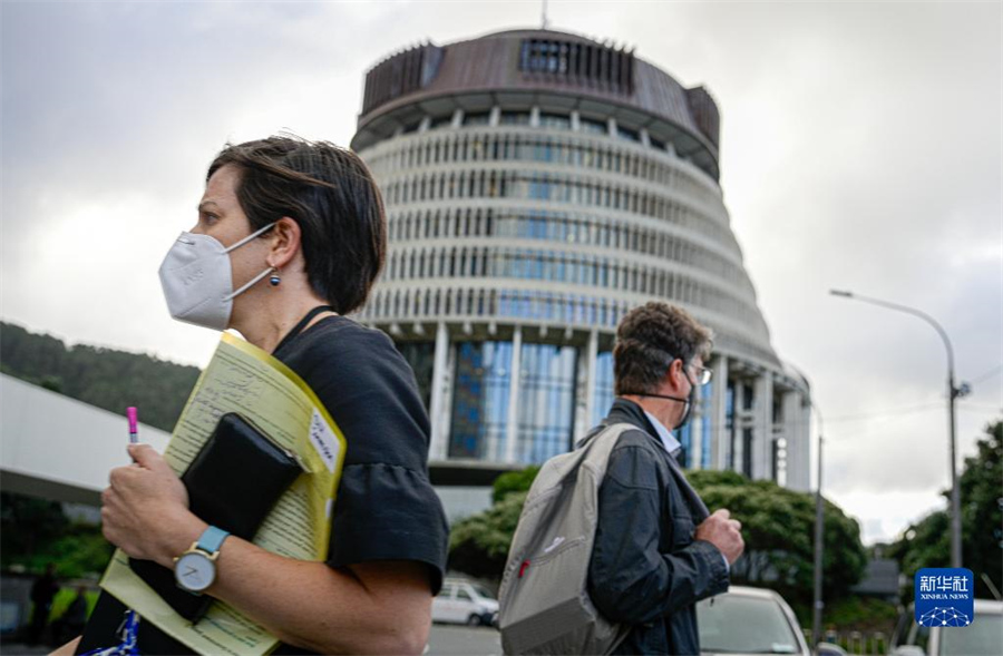 5月10日，在新西兰首都惠灵顿，戴口罩的行人经过国会大厦。新西兰卫生部10日通报，该国累计新冠确诊病例超过100万例。新华社记者 郭磊 摄