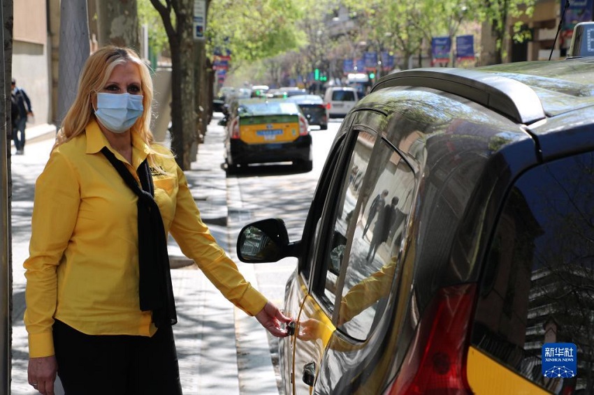 4月7日，在西班牙巴塞罗那，出租车司机洛拉・埃克斯波西托准备拉开出租车门。新华社发（伊斯梅尔・佩拉科拉摄）