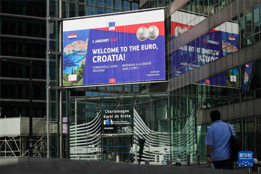 7月12日，在比利时布鲁塞尔，行人经过“欢迎克罗地亚加入欧元区”海报。新华社记者 郑焕松 摄