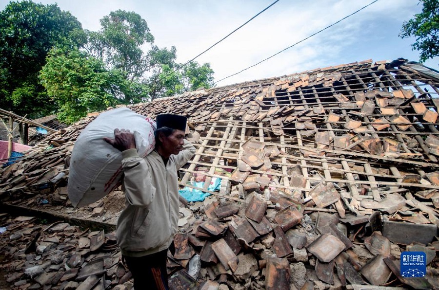 11月22日，在印度尼西亚西爪哇省展玉地区，一名男子从被地震损坏的房屋前走过。新华社发（赛普蒂安贾尔摄）