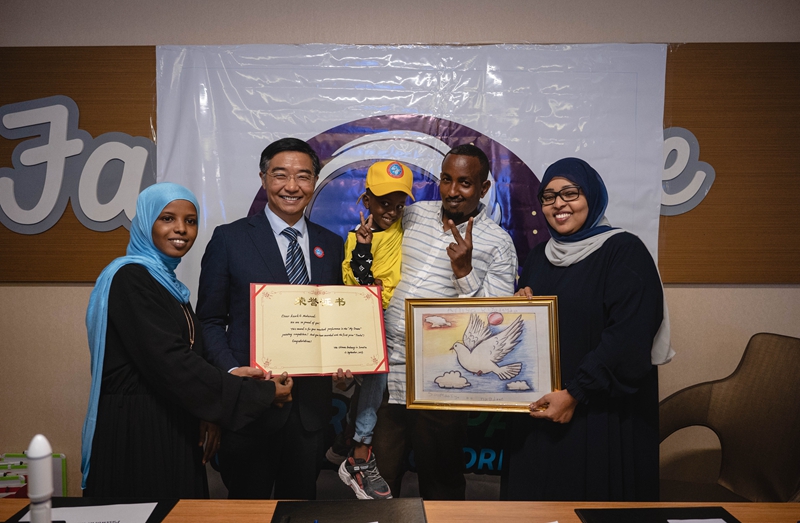 图为9月13日在索马里首都摩加迪沙拍摄，中国驻索马里大使费胜潮，索马里教育部国务部长（右），与获奖儿童及其父亲（中）和老师（左）合影。 记者 王冠森 摄
