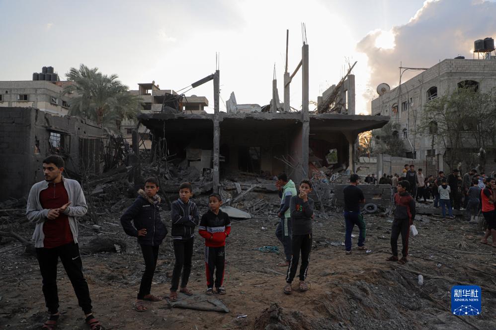 12月1日，人们聚集在加沙地带南部城市汗尤尼斯一处被炸的建筑周围。新华社发（里泽克・阿卜杜勒贾瓦德摄）