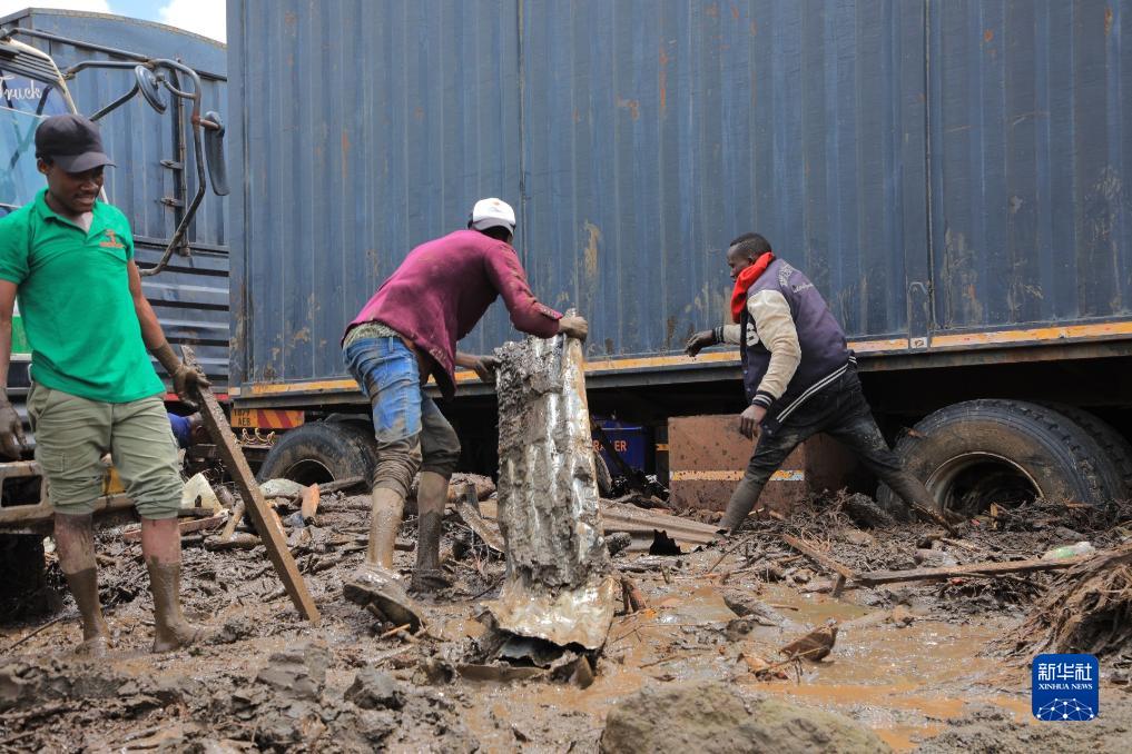 12月3日，在坦桑尼亚马尼亚拉地区，当地居民清理暴雨后货车旁的杂物和淤泥。新华社发