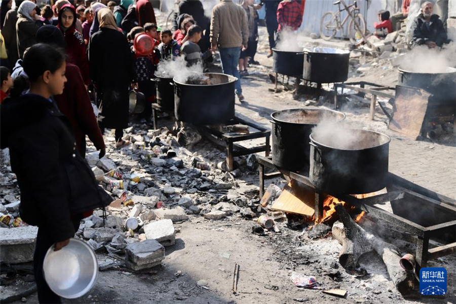 2月27日，在加沙地带北部的杰巴利耶难民营，人们等待领取食物。新华社发（穆罕默德・阿里摄）