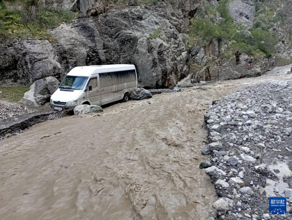 6月28日，在吉尔吉斯斯坦奥什州努卡特地区，一辆中巴车停在被泥石流冲毁的道路旁。新华社发（罗曼摄）
