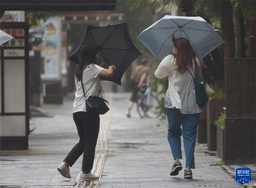 8月29日，行人在强风中走在日本鹿儿岛县鹿儿岛市街头。日本气象厅发布台风特别警报说，鹿儿岛县可能将遭遇前所未有的暴风天气、大浪和风暴潮，呼吁当地民众保持高度警惕。新华社/共同社