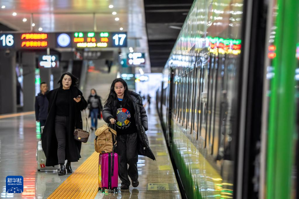 1月14日，乘坐D87次中老铁路国际旅客列车的旅客在昆明南站进站上车。新华社记者 胡超 摄