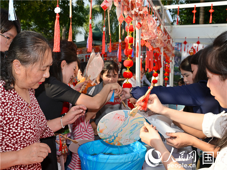 观众在“欢乐春节嘉年华”活动现场体验漆扇制作。人民网记者 谢佳君摄