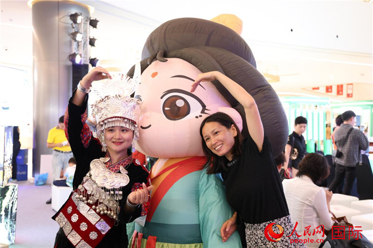 活动现场，泰国民众与身着少数民族服饰的重庆代表团旅游推介人员合影。人民网记者 杨一摄