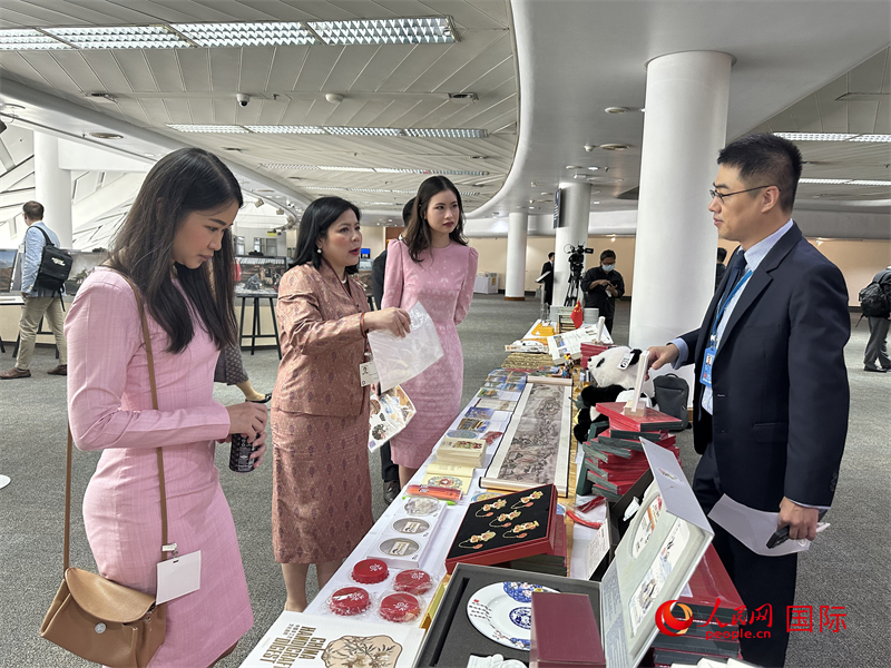 与会代表在中国展台前欣赏传统手工艺品感受中华文化。孙广勇摄