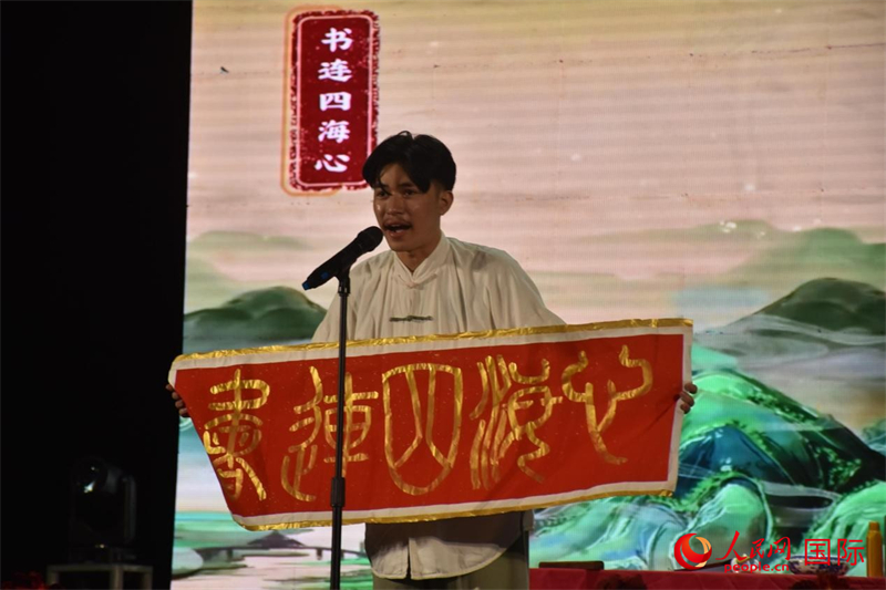 参赛选手文修竹同学在宣纸上挥毫泼墨，一笔一画书写出“书连四海心”的美好期许。人民网记者樊帆 摄