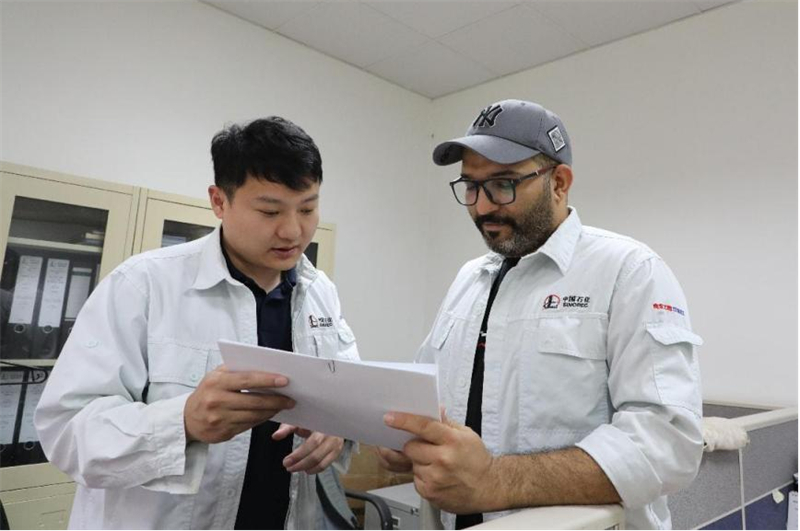 穆德海希尔（右）与中方员工在核对材料清单。中石化南京工程公司供图