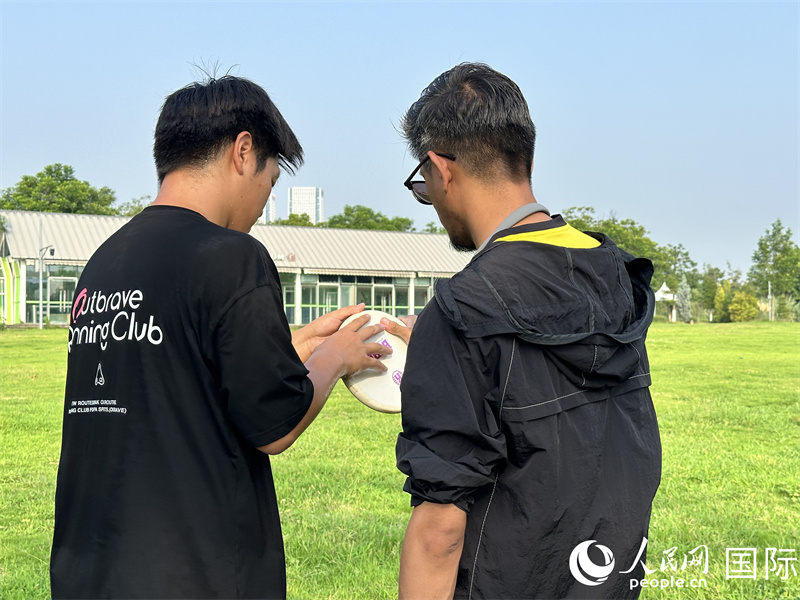 人民网外籍专家舒克里（右）学习掷准飞盘动作。 人民网 孙书宇摄