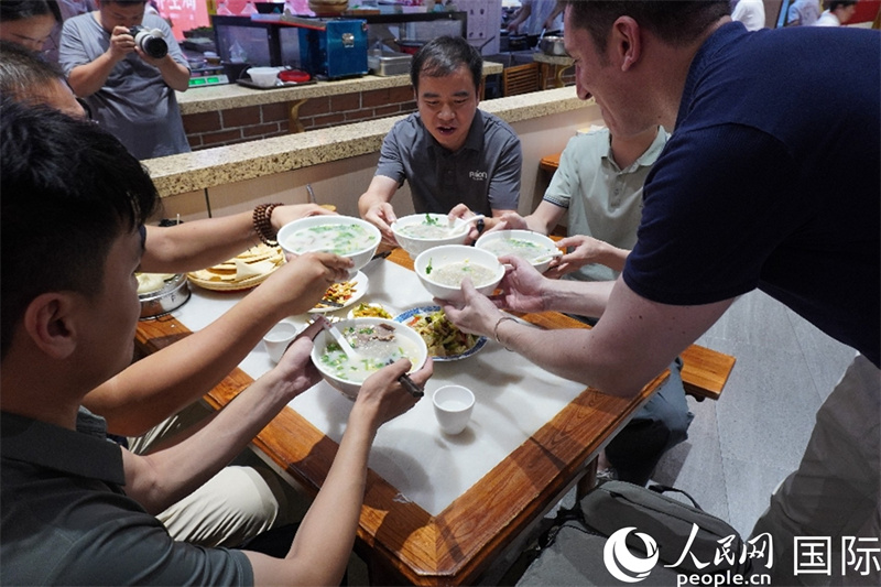 人民网外籍专家湖长明与当地食客用羊汤“干杯”。 人民网 喻亮摄
