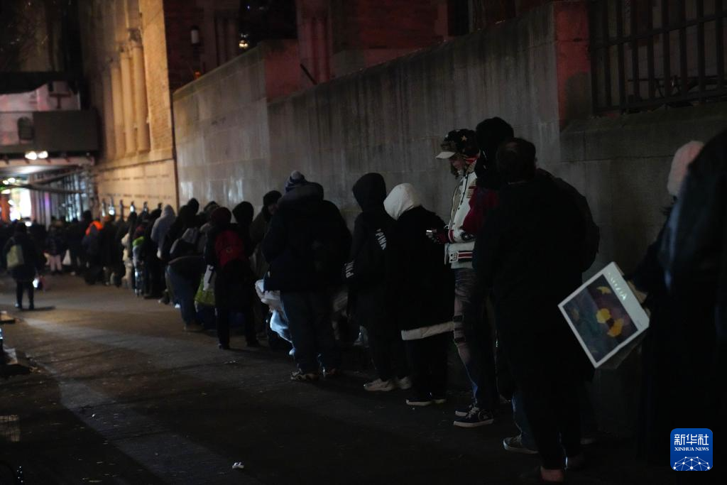 12月17日，在美国纽约曼哈顿的一处救助点，人们排队等待领取免费晚餐。新华社记者 张凤国 摄