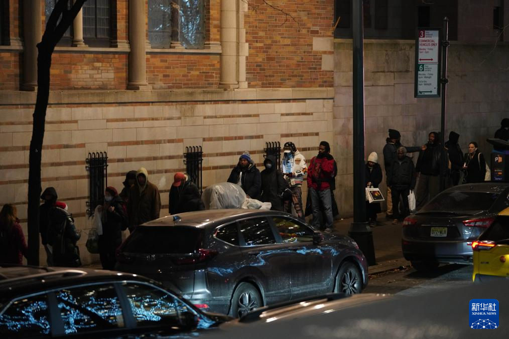 12月17日，在美国纽约曼哈顿的一处救助点，人们排队等待领取免费晚餐。新华社记者 张凤国 摄