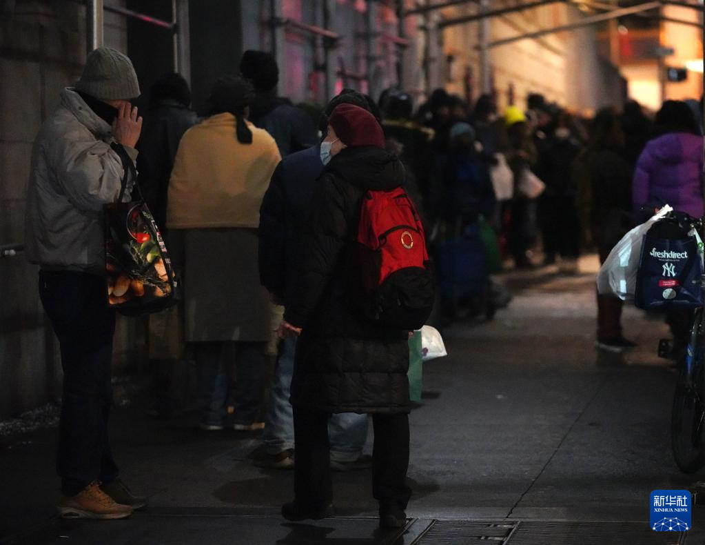 12月17日，在美国纽约曼哈顿的一处救助点，人们排队等待领取免费晚餐。新华社记者 张凤国 摄