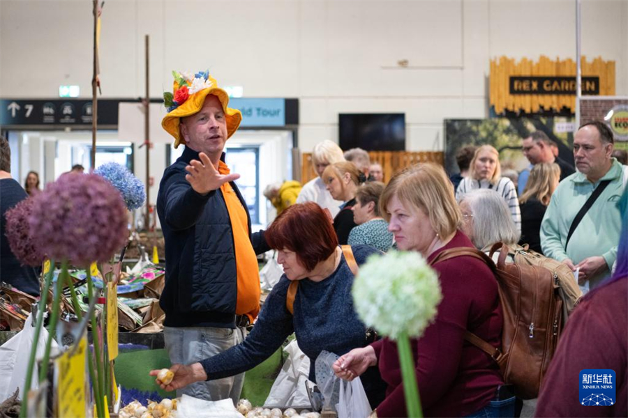 1月16日，在德国首都柏林，一名摊主（左一）在柏林国际绿色周现场叫卖花卉种球。新华社记者 张豪夫 摄