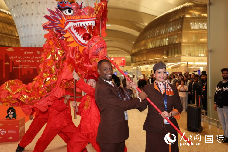 国航北京至阿布扎比首航开航仪式上，扎耶德国际机场工作人员体验中国舞龙。人民网记者 张志文摄