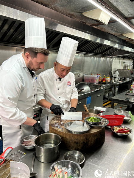 广东汕头，人民网外专柯明可向陈志毅师傅（右一）学习烹饪技艺。人民网 王潇平摄