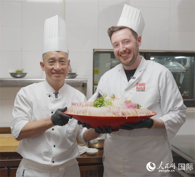 广东汕头，人民网外专柯明可与陈志毅师傅（右一）展示生鱼佳肴。人民网记者 刘宁摄