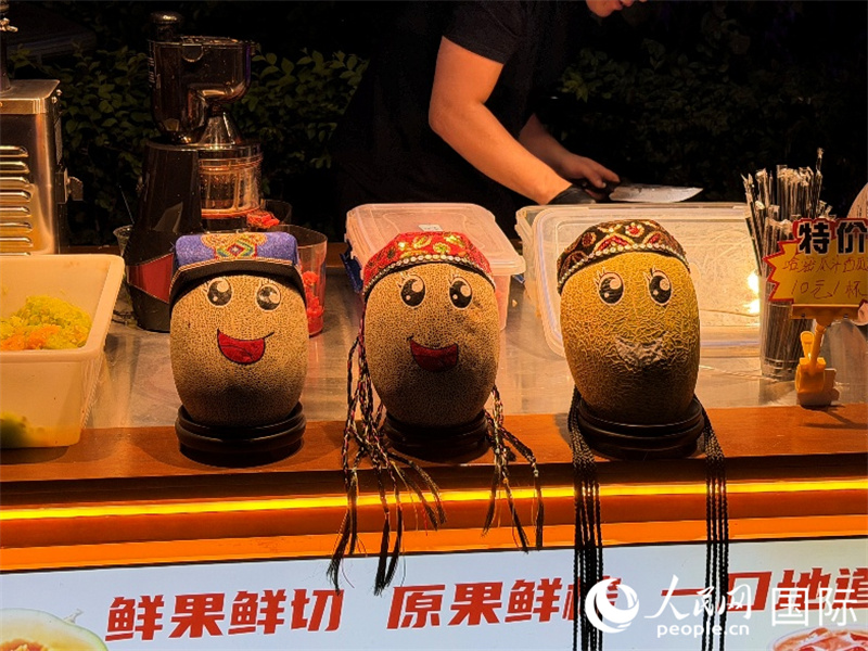 阿勒屯古街上，一位摊主给自己的哈密瓜画上表情。人民网 柯明可摄