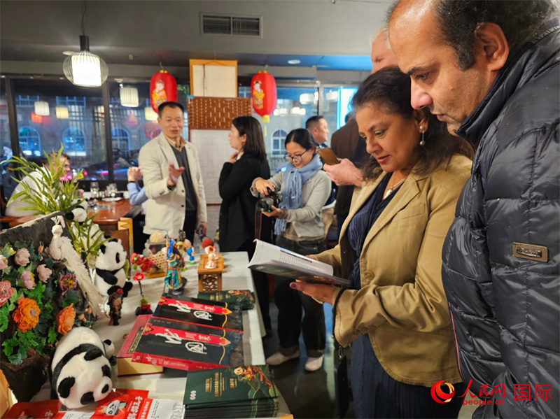 川渝非遗文化市集展位,海外旅行商翻阅美食介绍。人民网 徐量摄