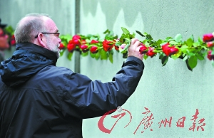 11月9日,一名德国人在残存的柏林墙前面进行追思。