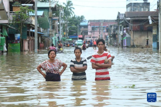   8月12日，人们在缅甸勃固镇被水淹没的道路上涉水前行。