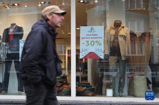  10月31日，一名男子从比利时布鲁塞尔一家贴有打折信息的店铺前走过。新华社记者 赵丁喆 摄