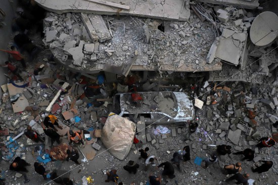 12月7日，在加沙地带南部城市汗尤尼斯，巴勒斯坦人查看遭以军袭击后的建筑废墟。新华社发（里泽克·阿卜杜勒贾瓦德摄）