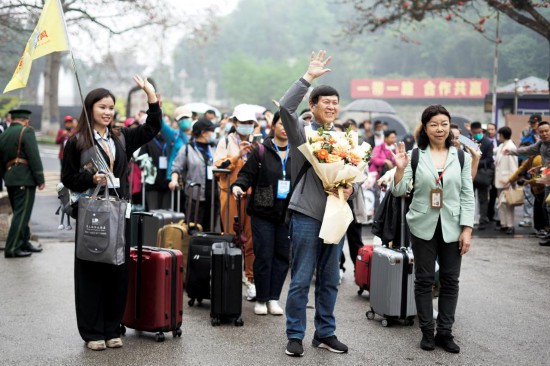 3月15日，在越南谅山省的友谊外洋港口，中国旅客向越方办当事人说念主员挥手问候。（新华社记者胡佳人摄）