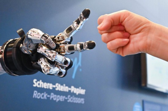 2024年4月23日，在德国汉诺威工博会上，参观者与一款智能机器人进行“石头剪子布”游戏。新华社记者任鹏飞摄